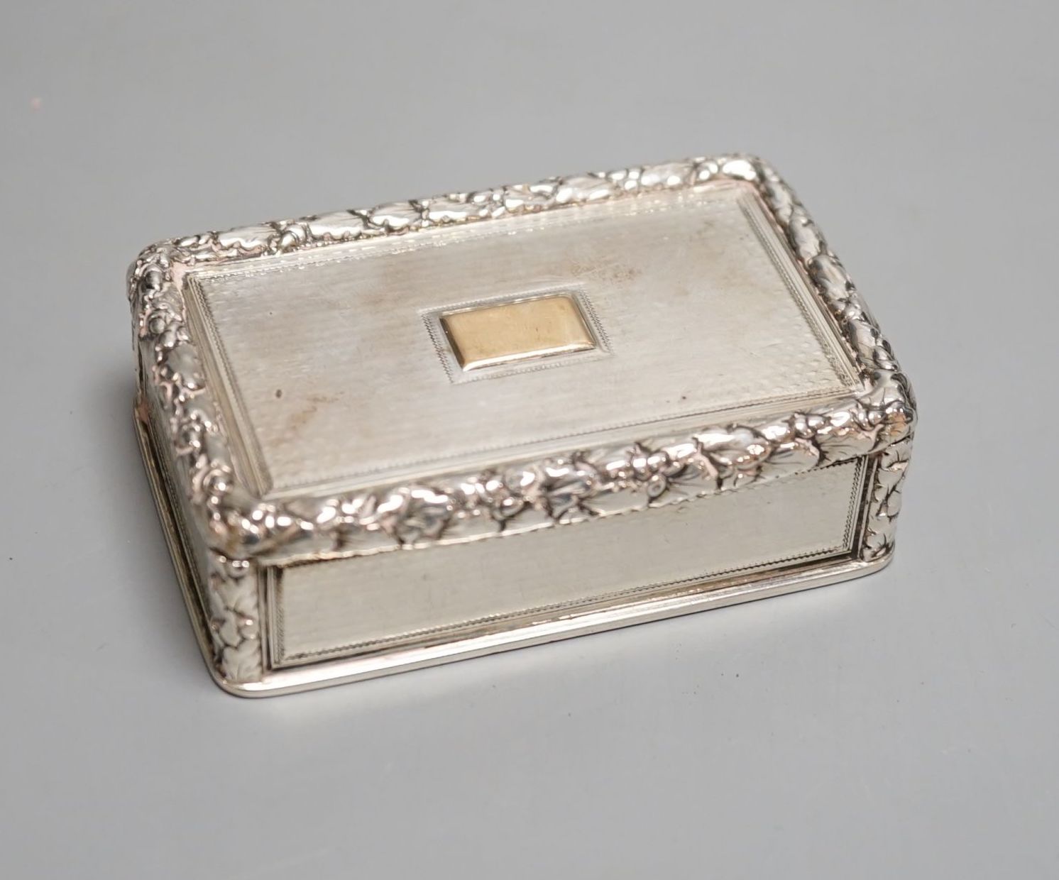A George IV engine turned silver rectangular snuff box, with yellow metal applique, Charles Rawlings, London, 1827, 82mm.